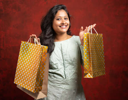 Happy Smiling Indian woman with shopping bags looking at camera - concept showing of shopaholic and holiday festival shopping sales and offersの写真素材