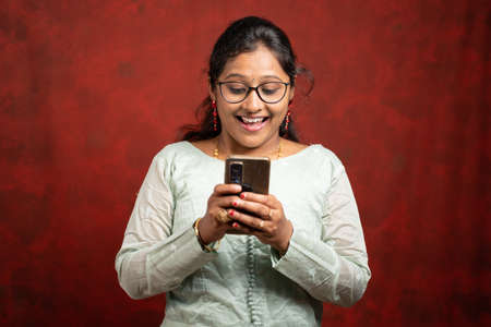 closeup shot of young indian woman surprised while using mobile phone -の写真素材