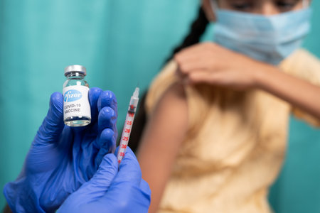 Maski, India - October 26, 2021 : selective focus on vaccine bottle - Kid with medical face mask...
