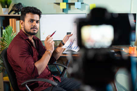 selctive focus on Trader explaing about stock market by recording camera at home - concept of E-teaching, live streaming and virtual classの写真素材