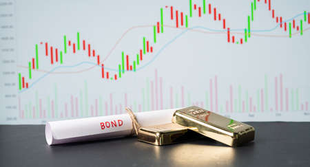 Concept of gold bond showing with Gold bars and Bond paper with Stock Market Graphs or charts in backgroundの写真素材