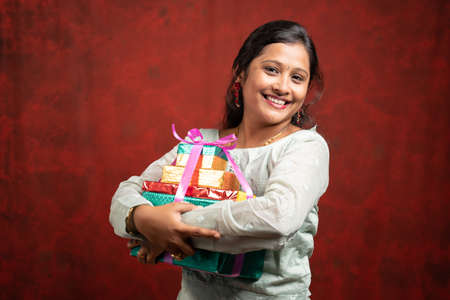 Happy smiling Indian Woman with gift boxes looking at camera - concept of gift present during festival holiday shoppingの写真素材