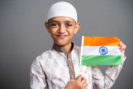 portrait shot of happy Muslim Kid with Indian flag in hand saluting by looking camera - conept of Nationalism, Patriotism, republic or independence celebrationの写真素材