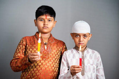 Hindu muslim kids mourning or praying by holding candles by looking at camera - concept of paying tribute and protect againt religious communalism.の写真素材