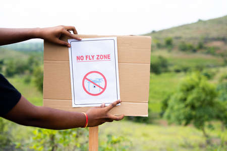 Close up shot of hands pasting No fly zone sign on board at drone Restricted area as safety...