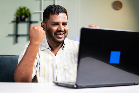 Celebrating Obese man by seeing good news mail on laptop while working at home - concept of employee got promotion or business deal, offer letter and won online lotteryの写真素材