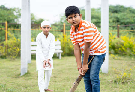 Multiethnic kids playing cricket at park during holiday vacation - concept of friendship, diversity...