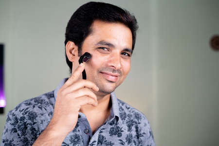 Handsome Young Man using derma roller on face as skincare therapy - concept of acne scarring and...