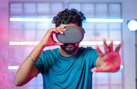 young professional gamer enjoying by playing realastic game experience on vr or virtual reality headset on neon light background - concept of modern gaming, technology and cyberspaceの写真素材