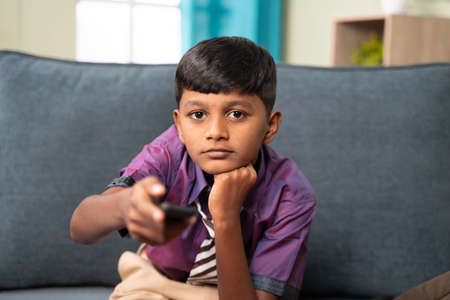 Kid to watch television or tv show after coming from school - concept of childhood movie addiction and unhealthy lifestyle.の写真素材