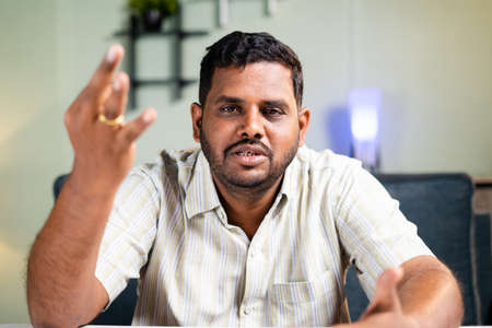 Fat man confidently explaining or talking by looking at camera on video call - concept of online...
