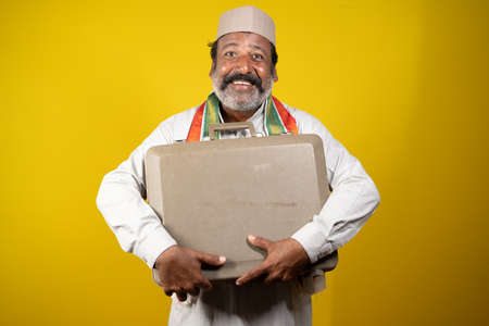 Smilling corrupt indian politician holding or Embracing brief case by looking at camera - concept...