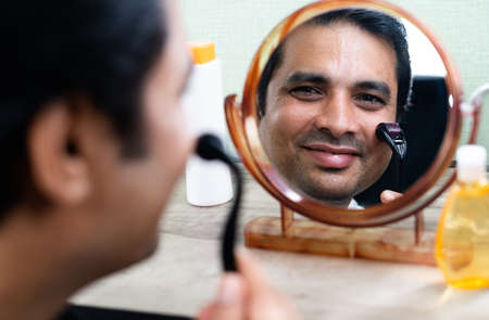 Handsome young Man using derma roller on face by looking at mirror - concept of treatment or therapy...