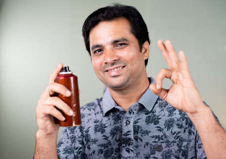 happy handsome young man recommending perfume by looking at camera- concept of freshness, mood...