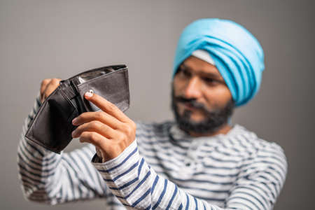 Worried young sikh man for not having money in wallet - concept of debt, bankrupt and unemployment.の写真素材