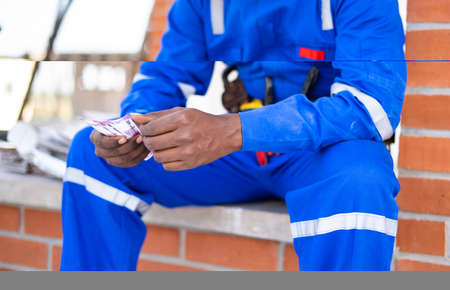 Close up shot of unrecognizable labour counting Money - concept of repairman received payment for completing work, blue collar jobs and earnings.の写真素材