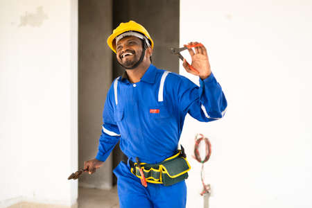 Repairman dancing with tool in hand for successful completion of work - concept happiness, joyful...