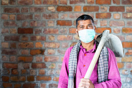 confident construction worker with medical face mask looking camera at workplace - concept of back...