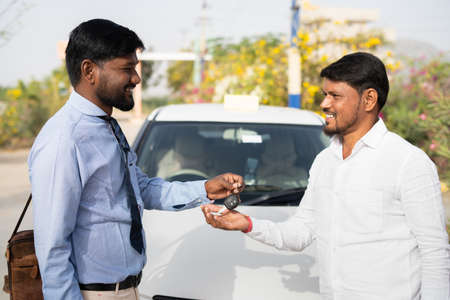 Cab driver receiving car key from bank officer in front of car - concept of financial support from...