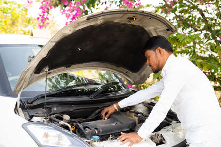 indian cab driver checking or repairing car engine after traveling - concept of self car...
