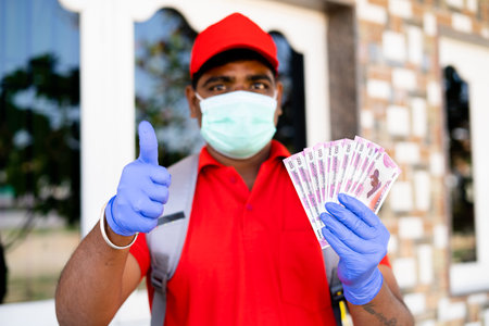 Focus on money, happy delivery boy with medical face mask counting Money - concept of daily earings...