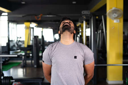 young man busy doing neck rotation warm up exercise at gym - concept of wellness, healthy lifestyle and work out sessionの写真素材