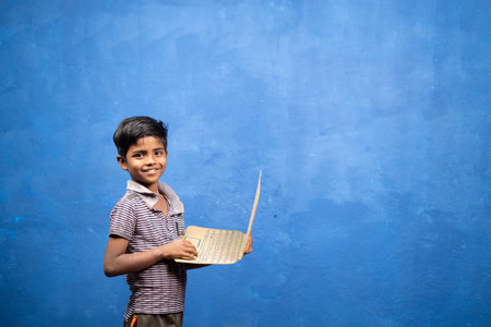 Smiling boy kid playing with cardboard laptop by looking at camera - concept of entertainment, childwood playful lifestyle and povertyの写真素材