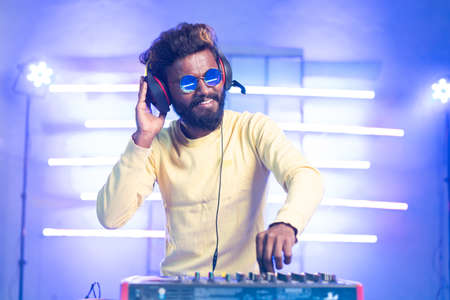 exicted dj sound device oprator with headphones by dancing at club - concept of entertainment,...