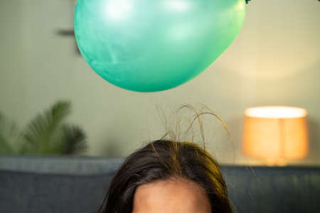 close up shoto of kids playing by placing balloon to attracting hair - conept of static cling home science experiment and learning.の写真素材