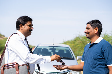 Car mechanic receiving car key from businessman in front of car on road - concept of mortgage, car rental nusiness and financial or banking systemの写真素材