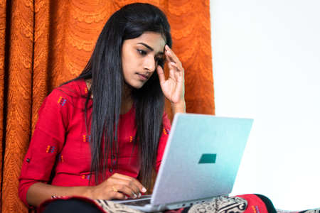 Worried young teenager girl while using laptop at home - concept of exam failure, job rejection and cyber bullyingの写真素材