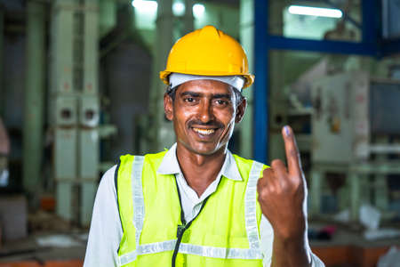 industrial worker showing Ink marked finger after voting at electionby looking at camera - concept of responsibility, freedom and democracy.の写真素材