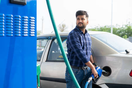 young man fueling car at petrol or gas filling station - concept of transportation, transportation and self-service.の写真素材