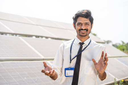 Professional engineer explaining about solar panel installation at farm land by looking at camera - concpet of renewable energy, eco friendly and technologyの写真素材
