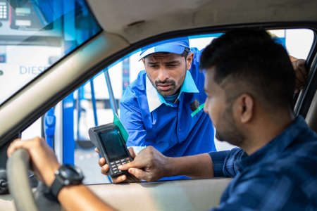 Customer paying using credit card at petrol filling station by swiping for refueling car - concept of digital casless payemt, secure transaction and banking.の写真素材