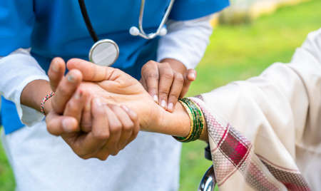 close up shot of Doctor checking pulse rate of womanby holding hand at park - concept of medicare or healthcare treatment and professional occupationの写真素材