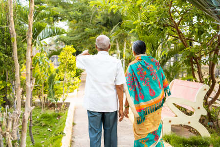 Back view shot of senior couples during morning walk at garden - conept of bonding, relationship and healthy relaxed lifestyleの写真素材