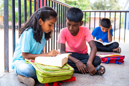 focus on boy Teenage kids busy studying or preparing before examination while sitting on school corridor - concept of education,childhood development and learning.の写真素材