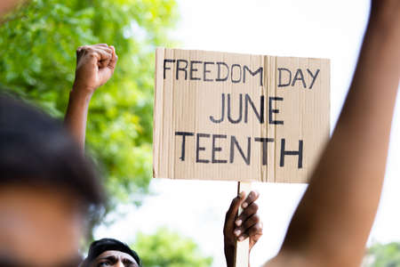 concept of Juneteenth freedom day march showing by close up protesting hands sign board - concept of activism, justice and demonstrationの写真素材