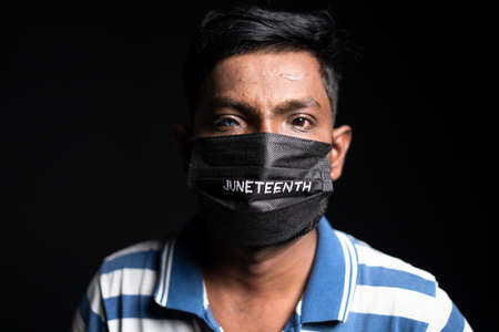 young man with juneteenth medical face mask looking at camera during coronavirus covid pandemic in...