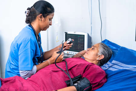 Nurse or doctor checking bp or blood pressure of senior sick patient at hospital on bed - concept of treatment, routine checkup and healthcareの写真素材