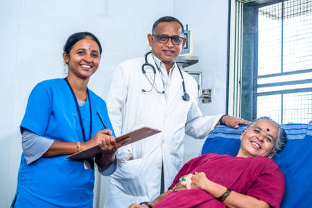 Happy smiling doctor, patient and nurse looking at camera during ward visit at hospital - concept of recovery, medicare and treatment.の写真素材