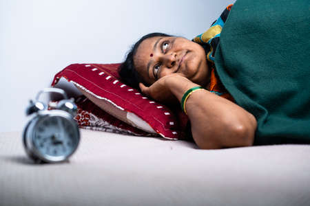 middled aged woman suffering from sleepless during night at bedroom - concept of nightmare, insomnia and sadness.の写真素材
