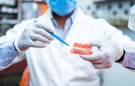 close up shot of Dentist hands at clinic advising or telling about cavity of tooth problems by...