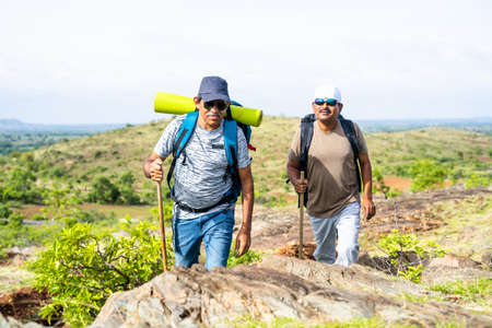 Middle aged hiker with backpack climbing mountian - concept of freedom, active leisure lifestyle and...