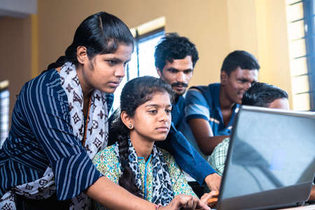 Groups of students seriously using laptop at classroom - concept of technology, education and self...
