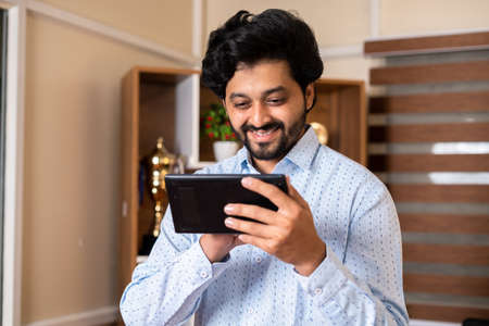 Happy smiling corporate employee using digital tablet at office - concept of Project approval,...