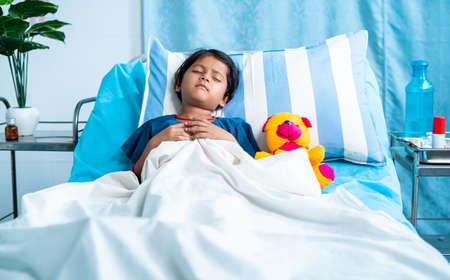 Sick girl child with teddy bear sleeping on bed at hospital - concept of medial treatment, illness and childcare.の写真素材