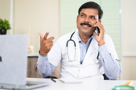happy smiling doctor busy talking with patient on mobile phone call - concept of communication,...