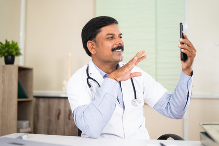 Doctor on video call with patient on mobile phone at hospital - concept of mhealth, visrtual medical consultation and technologyの写真素材